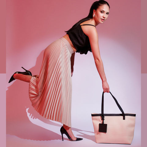 Woman styling The Bella Tote, a genuine leather tote bag designed for everyday use, shown in a fashion lifestyle setting.